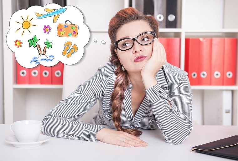 Gelangweilte Frau im Büro träumt von Urlaub