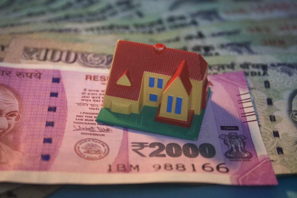 Faule Kredite beispielhaft dargestellt mit Haus auf indischem Geldschein