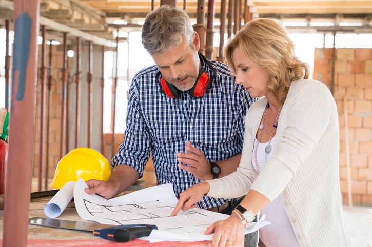 Zwei Personen besprechen Bauplan auf Baustelle