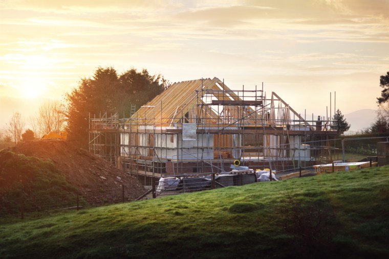 Ein Haus welches gebaut wird. Außenrum ist ein Geländer aufgebaut.