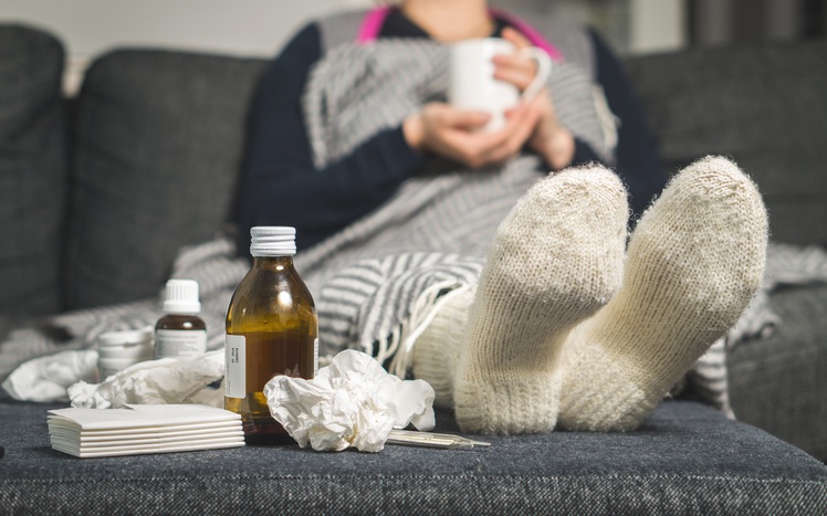 Frau liegt mit Erkältung auf dem Sofa