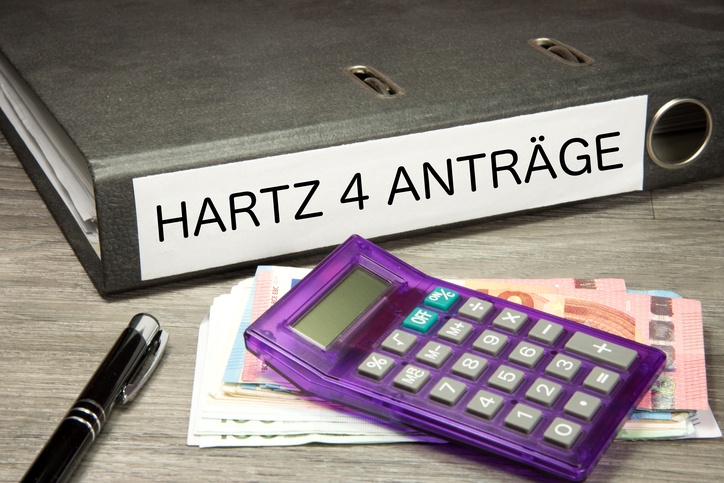 Ein Taschenrechner, Euro Geldscheine und ein Ordner mit Hartz 4 Anträgen