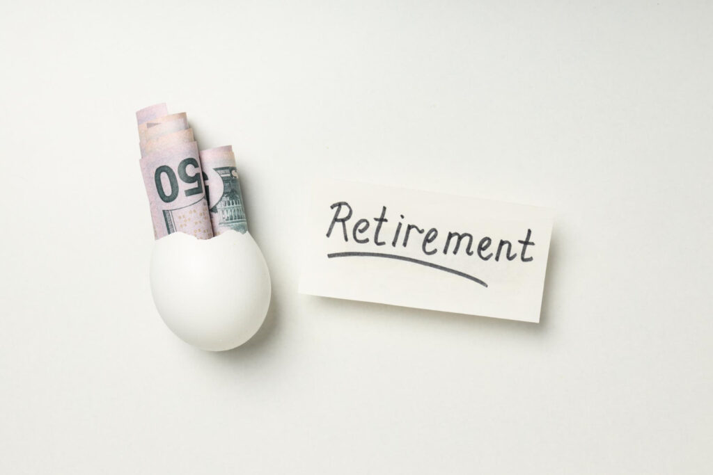 ymbol für Altersvorsorge: Ei mit Geldscheinen und Karte mit 'Retirement'